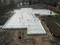 Budowa domu: przygotowane słupy fundamentowe, zbrojenie i izolacja płyty fundamentowej.