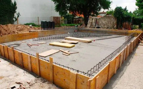 Drewniane szalunki i zbrojenie czekają na beton, tworząc fundamenty z kamienia.