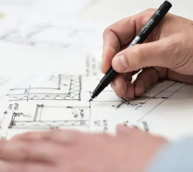 Dłoń rysuje plany architektoniczne, uwzględniając objętość właściwą.