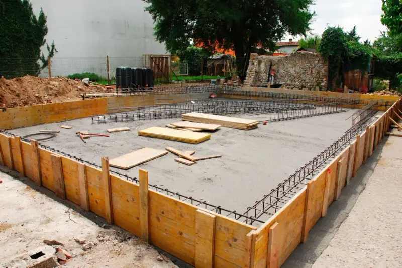 Drewniane szalunki i zbrojenie czekają na beton, tworząc fundamenty z kamienia.